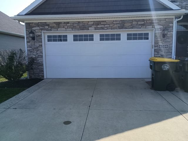 White carriage-style double garage door with windows on a stone-front home