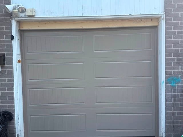 Taupe long-panel garage door on a brick townhouse