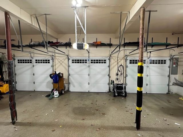 Interior view of three white garage doors with window rows and a Chamberlain opener